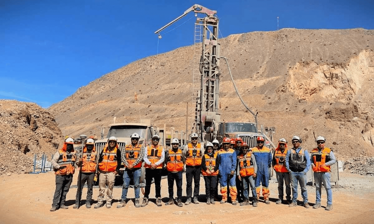 Mining site team in front of a drilling rig