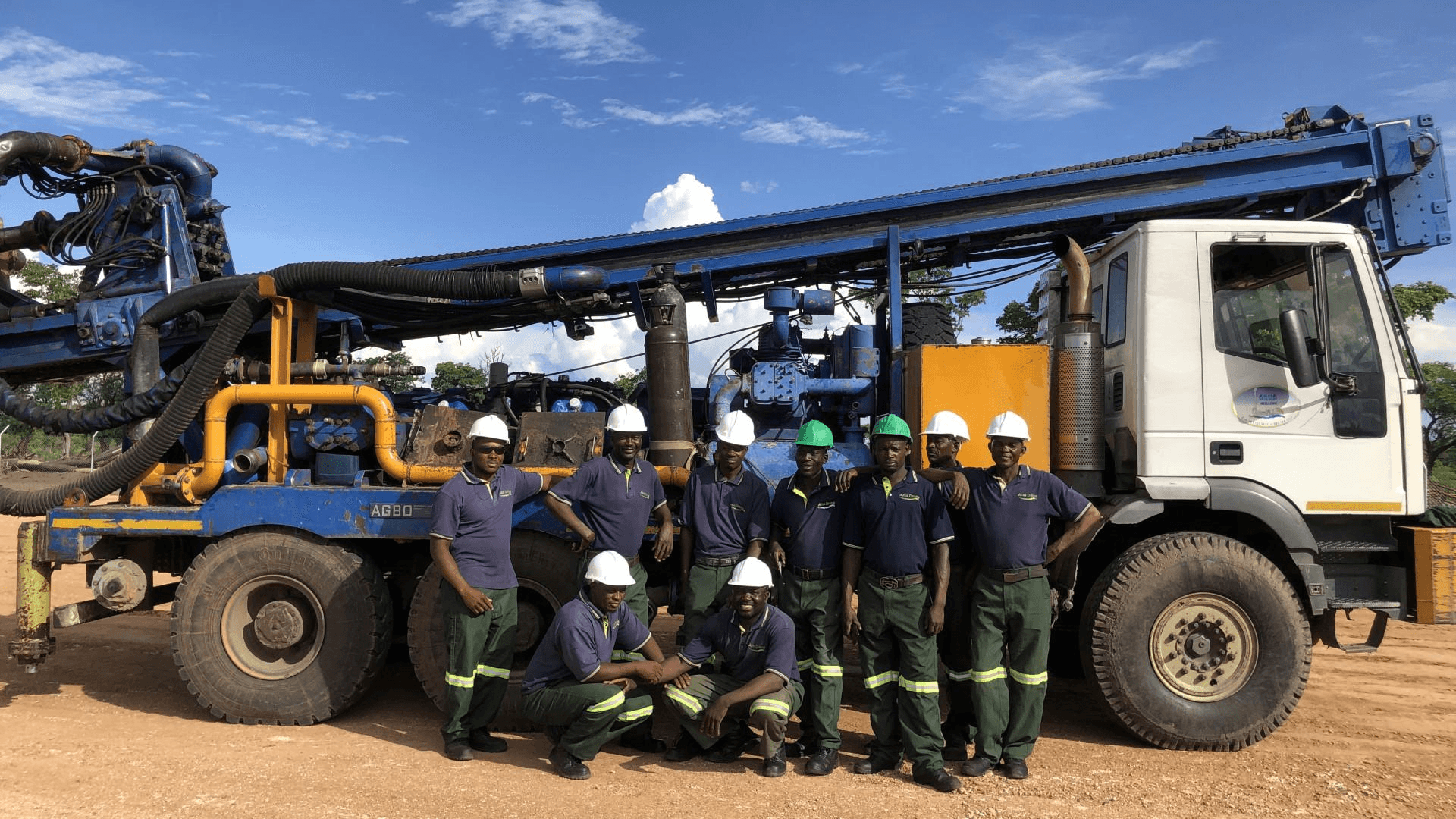 Water well drilling team beside a truck-mounted rig