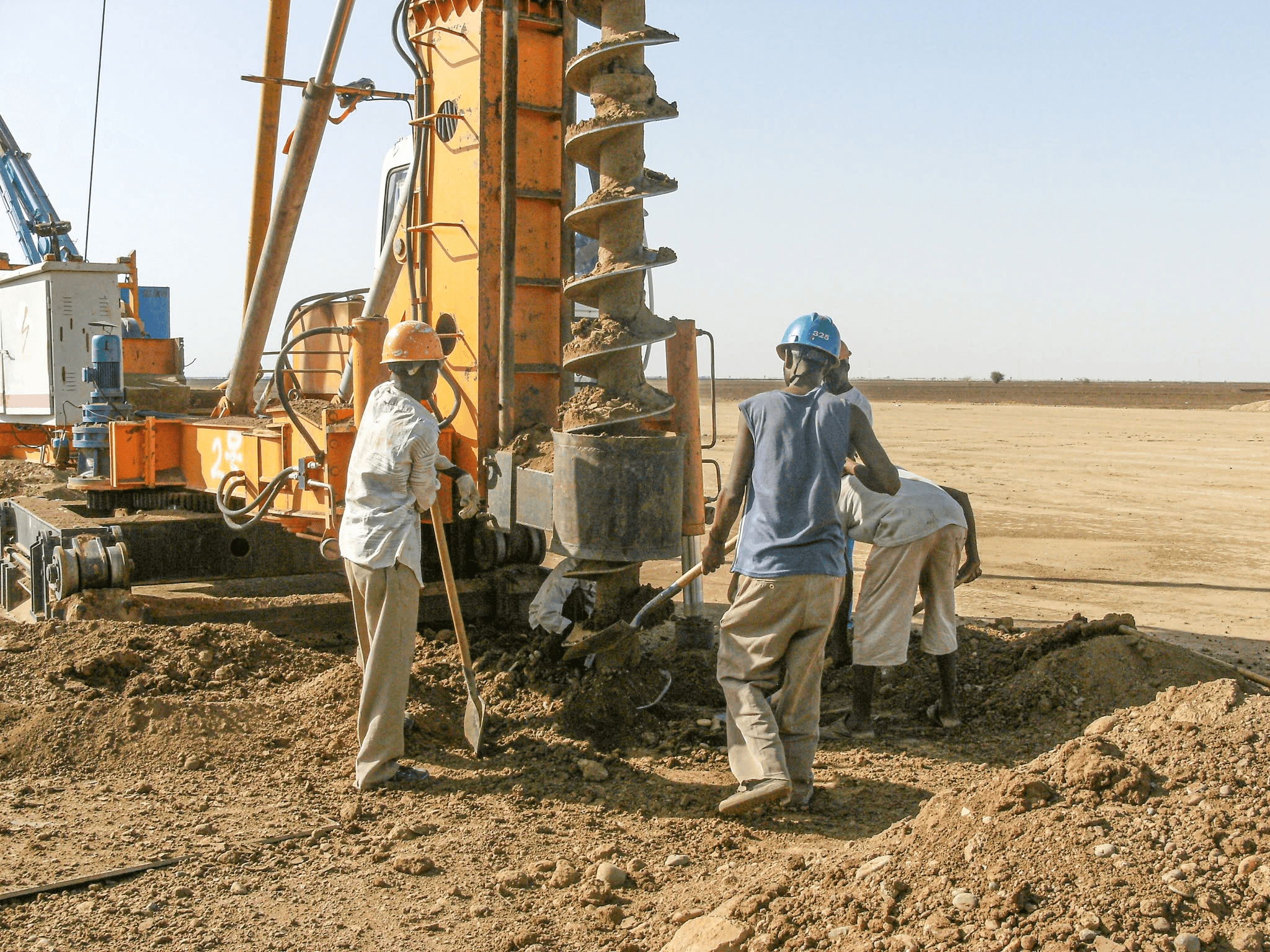 Operators working with an auger drilling rig