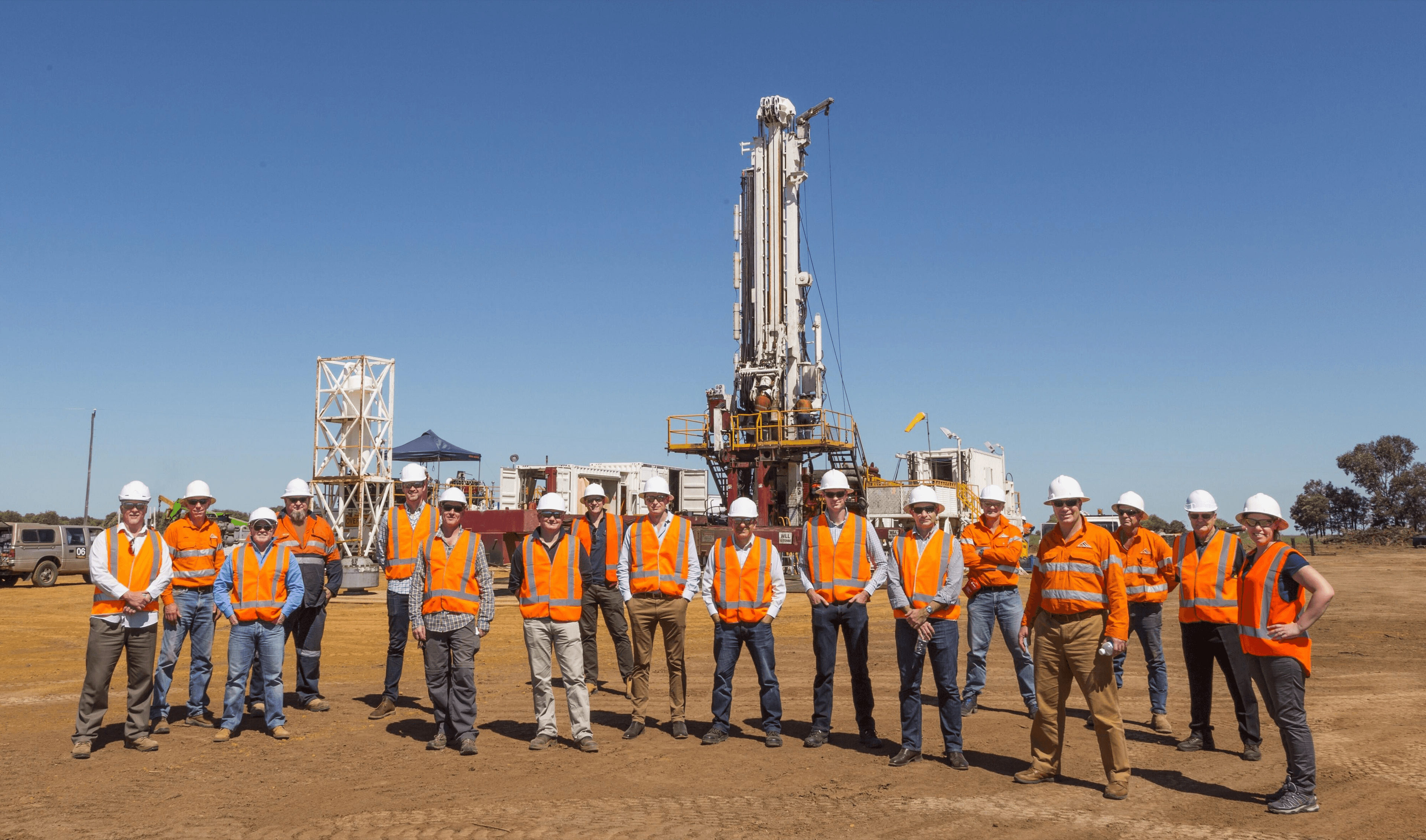 Field drilling team standing in front of a site rig