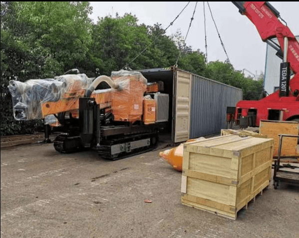 Wrapped drilling rig being lifted beside a shipping container